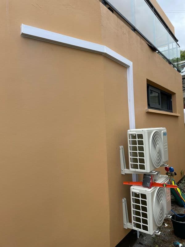 Pose de deux unités extérieures de climatisation sur façade beige à La Réunion