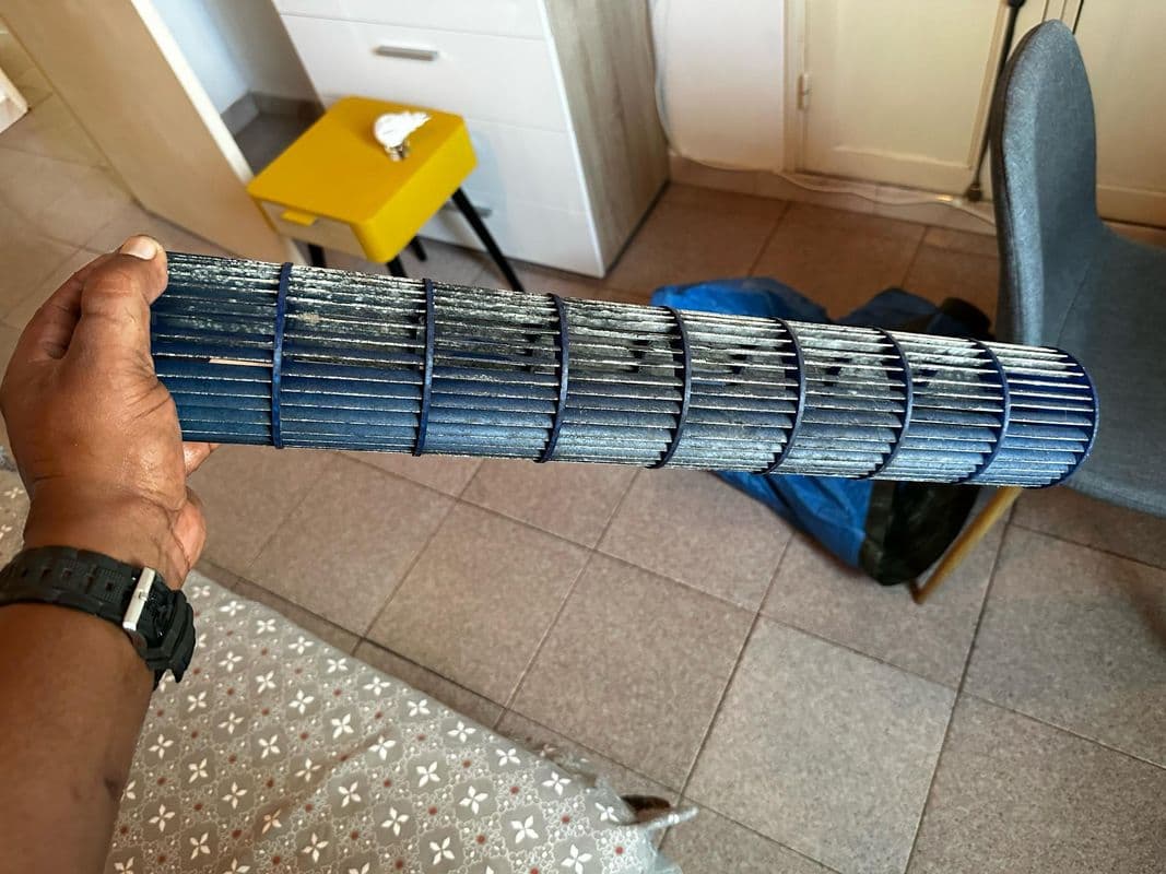Rotor de climatiseur encrassé avant entretien — couche de poussière noire visible